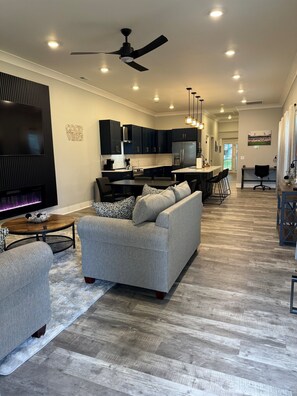A modern living room with a grey sofa, a TV, and a fireplace. - The TriFecta At Churchill Downs (Louisville)