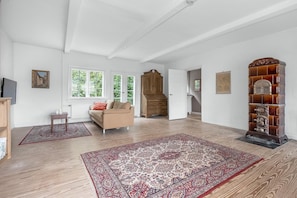 A spacious room with a large wooden cabinet, a sofa, and a patterned rug.