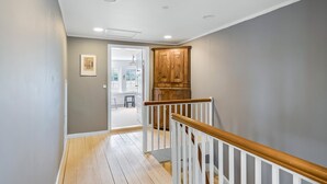 Una escalera con barandilla de madera, piso de madera y una puerta que da a otra habitación.