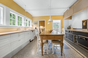 A kitchen with a wooden table, white cabinets, and a view of greenery outside.