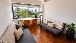 A modern living room with a sofa, chairs, a dining table, and a large window with a city view. - Luminous Home Studio with privileged view to the Park. Steps away from Metro Bilbao. Wifi (Providencia)