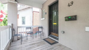 Een veranda met drie stoelen, een deur met het cijfer 49 en een brievenbus.