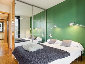 A modern hotel room with a large bed, two bedside lamps, a mirror, and a green wall. - Immerse in Barcelona – 2 & 3 Bedroom Units with Terrace Options (Barcelona)