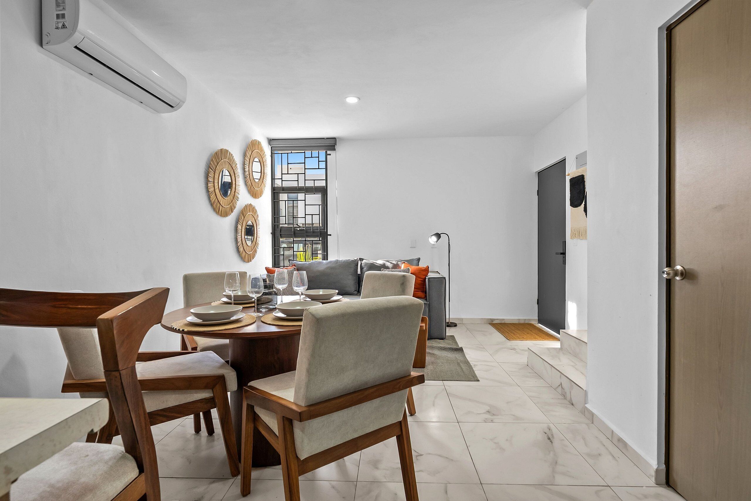 A dining area with a round table, chairs, and a window with blinds.