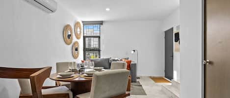 A dining area with a round table, chairs, and a window with blinds.