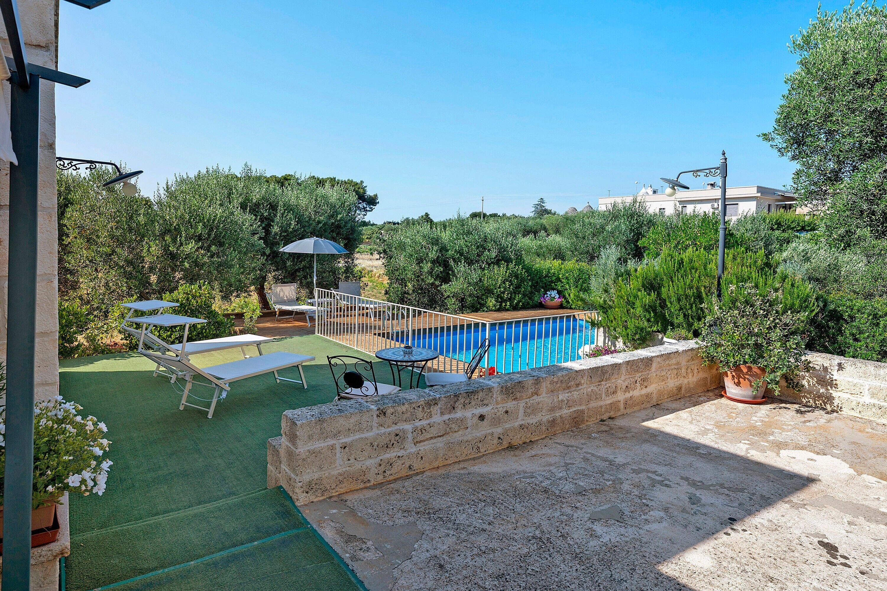 A rooftop pool area with a diving board, lounge chairs, and a table.