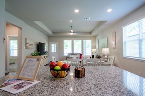 Una cocina amplia con encimeras de granito, un frutero y un comedor con mesa y sillas.