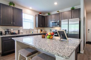 A modern kitchen with dark cabinets, stainless steel appliances, and a granite countertop.