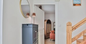 Ein Flur mit blauem Schrank, einem Spiegel, einer Lampe, einem Holzschrank, einem roten Stuhl und einer Holztreppe.