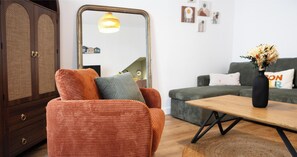 Ein Wohnzimmer mit einer Couch, einem Couchtisch, einem Sessel, einem Schrank und einem Spiegel.