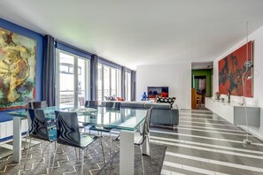 Ein modernes Wohnzimmer mit einem Glastisch, Sofas und einem Fernseher.