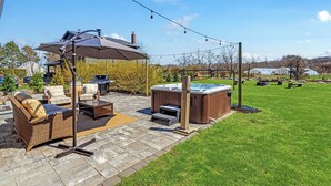 Un patio con arredi da esterno, una vasca idromassaggio e una zona coperta.