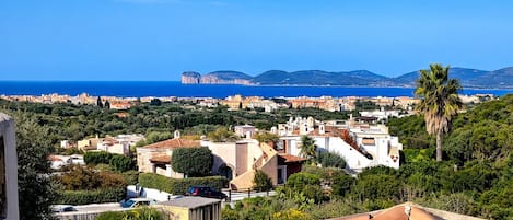 A coastal town with terracotta rooftops, Mediterranean architecture, and a view of the sea and mountains.