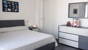 Et moderne soveværelse med seng, natbord, kommode, spejl og et klimaanlæg.