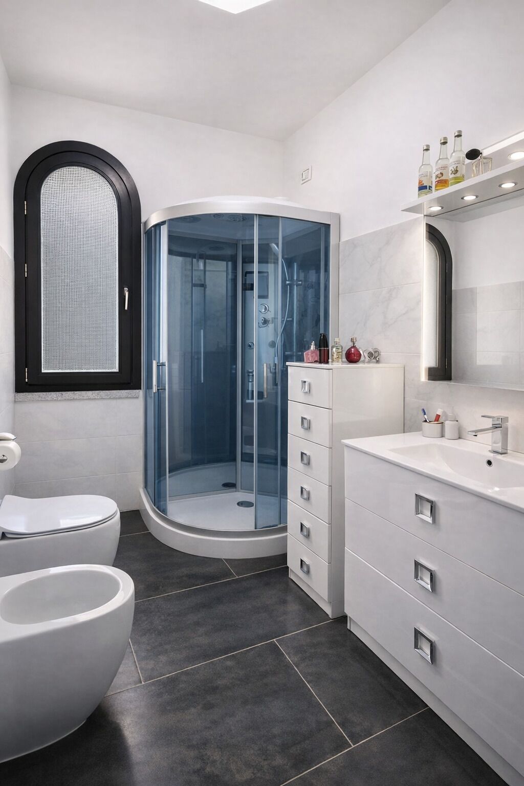 Une salle de bain moderne avec une douche à parois de verre, des toilettes blanches, un meuble-lavabo avec un miroir et une fenêtre à cadre noir.
