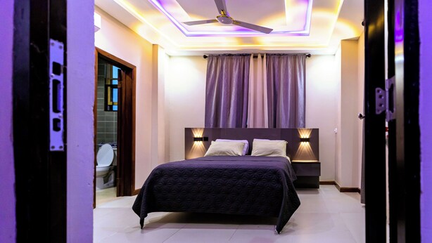 Ein Schlafzimmer mit einem Bett, einem Deckenventilator und einem Nachttisch mit Lampe.