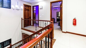 Eine Treppe mit hölzernen Geländern, ein Feuerlöscher an der Wand und eine Deckenleuchte.