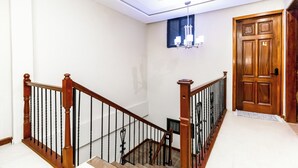Eine Treppe mit Holzwerteln und einem Chandelier, die zu einer Holztür führt.