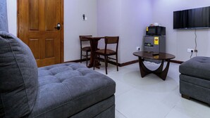 Ein Wohnzimmer mit Sofa, Tisch, Fernseher und Mikrowelle.