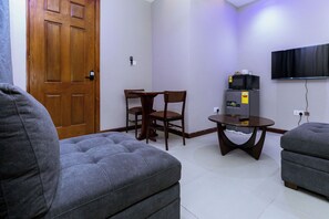 A living room with a sofa, a table, a TV, and a microwave. - Davina's Villa - Private 1BR Escape - Apt3 (Kumasi)
