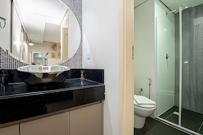 Et moderne badeværelse med et stort spejl, en sort bordplade, et håndvask og et toilet.