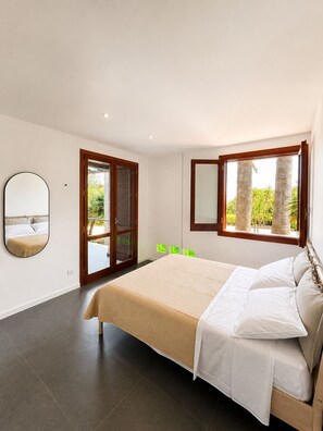 Ein Schlafzimmer mit einem Bett, einem Spiegel, einem Fenster und einer Tür, die zu einem Außenbereich führt.