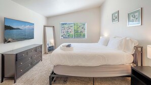 Ein Schlafzimmer mit Bett, Kommode, Fenster und Bildern an den Wänden.