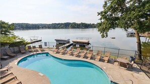 A swimming pool with lounge chairs and a view of a lake. - Delton Dawn - Luxury at Delton Grand (Wisconsin Dells)