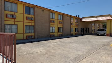 Un motel a più piani con facciata gialla, ampie finestre e un’area di parcheggio coperta.
