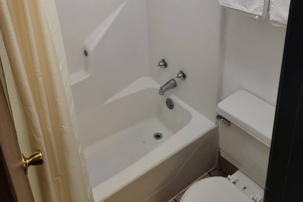 A bathroom with a shower, bathtub, toilet, and a towel rack.