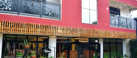 A two-story building with a red facade, a 'Bamboo Restaurant' sign, and potted plants in front.