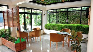 A modern indoor space with a seating area, large windows, and potted plants. - Sophies Garden Hotel (Makutano)