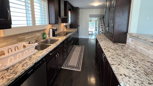 A kitchen with dark wood cabinets, granite countertops, a stainless steel sink, and a view into the dining area. - Spacious 3BR Toronto Home Near Downtown (Toronto)