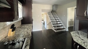 A kitchen with dark wood cabinets, a marble countertop, a stainless steel range hood, and a black stove. - Spacious 3BR Toronto Home Near Downtown (Toronto)