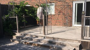 A wooden deck with a metal gate, a brick house, and a potted plant. - Spacious 3BR Toronto Home Near Downtown (Toronto)