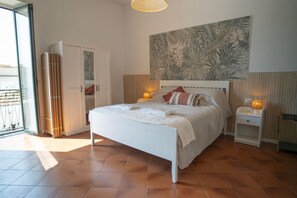 Ein Schlafzimmer mit Bett, Nachttischen, einer Wandleuchte, einer Schiebetür und einem großen Wandbild mit Blumenmuster.