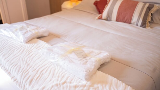 A neatly made bed with a white comforter and pillows, a bedside table with a lamp, and a striped pillow on the headboard. - Modern Suite and Open Space Bedroom• 200 meters from Sea • into Historic Center (Salerno)