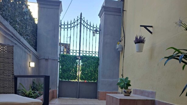 A table with a glass jar, a spoon, and a cup, set against a wall with a gate and potted plants. - Comfortable house with 2 rooms and full kitchen ideal for families and groups of friends (Napoli)