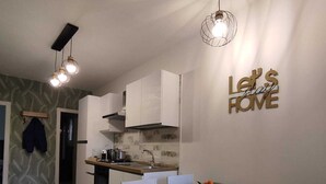 A modern kitchen with white cabinets, a dining table set with plates and glasses, and a 'Let's Stay Home' sign on the wall. - Comfortable house with 2 rooms and full kitchen ideal for families and groups of friends (Napoli)