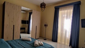A bedroom with a bed, a wardrobe, a desk, and a floor lamp. - Comfortable house with 2 rooms and full kitchen ideal for families and groups of friends (Napoli)
