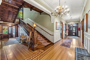 A grand staircase with a wooden finish, a chandelier, and a carpeted area. - Stay in a piece of history! (Pawtucket)