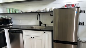 A kitchen with white cabinets, a stainless steel refrigerator, a dishwasher, and a microwave.