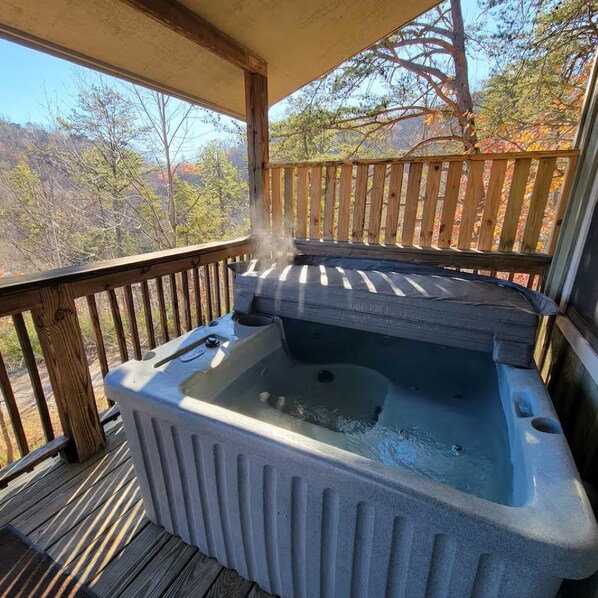 A hot tub on a wooden deck with a view of trees. - Huckleberry Cabin-Private (Sevierville)