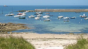 Een kustgezicht met tal van boten die in kalm water liggen ankeren, een zandstrand en rotsachtige landtongen.