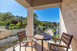 A balcony with a table and two chairs, overlooking a stone wall and a view of trees and hills. - Luxurious Villa Arthur in Corfu | Heated Pool & Jacuzzi, Sea Views, Outdoor BBQ (Kassiopi)
