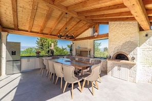 A modern kitchen with a large island, stone walls, and a view of the mountains. - Luxurious Villa Arthur in Corfu | Heated Pool & Jacuzzi, Sea Views, Outdoor BBQ (Kassiopi)