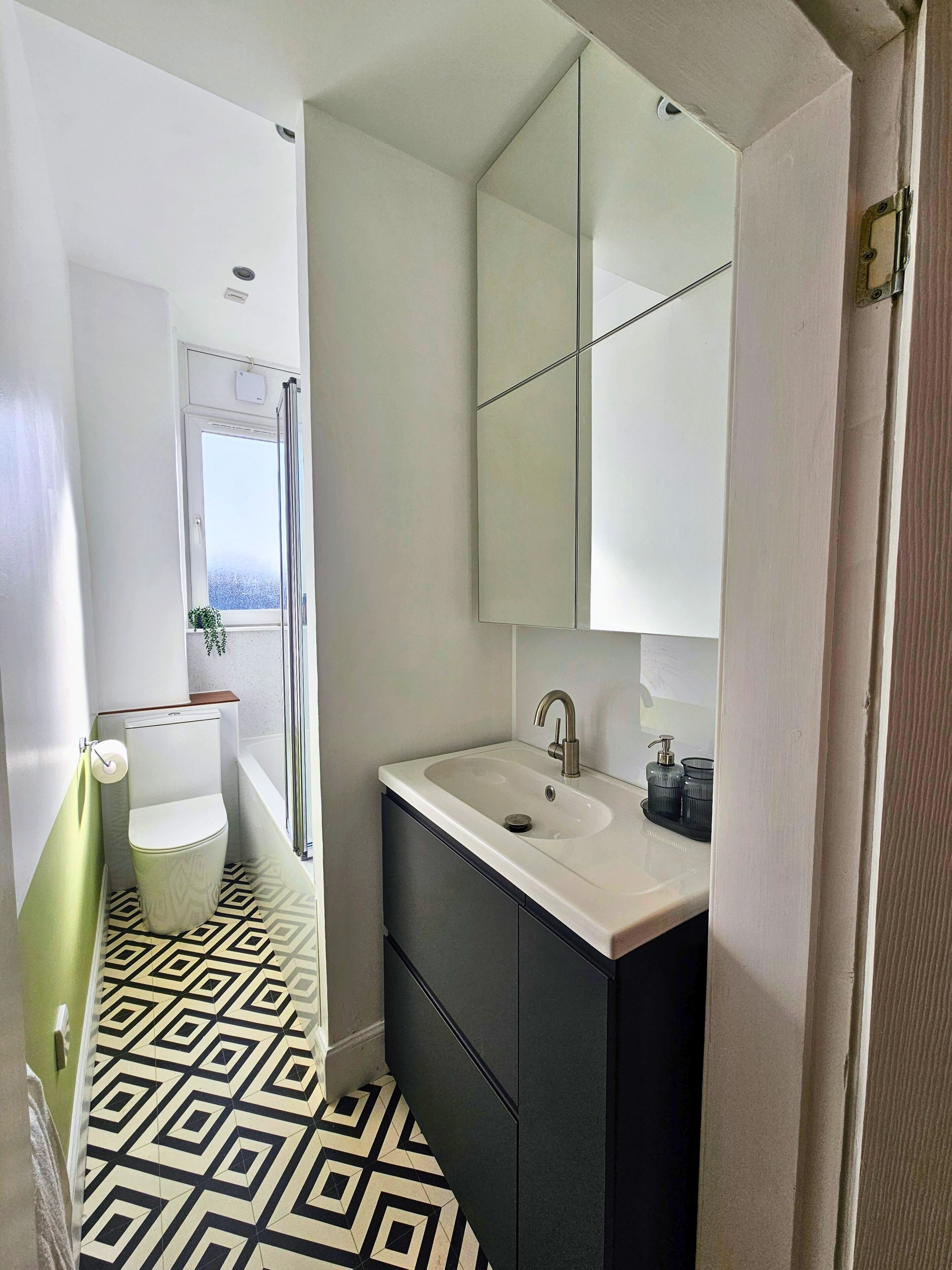 A bathroom with a toilet, sink, mirror, and patterned floor.