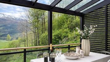 A table set with glasses and a vase, overlooking a mountainous landscape.