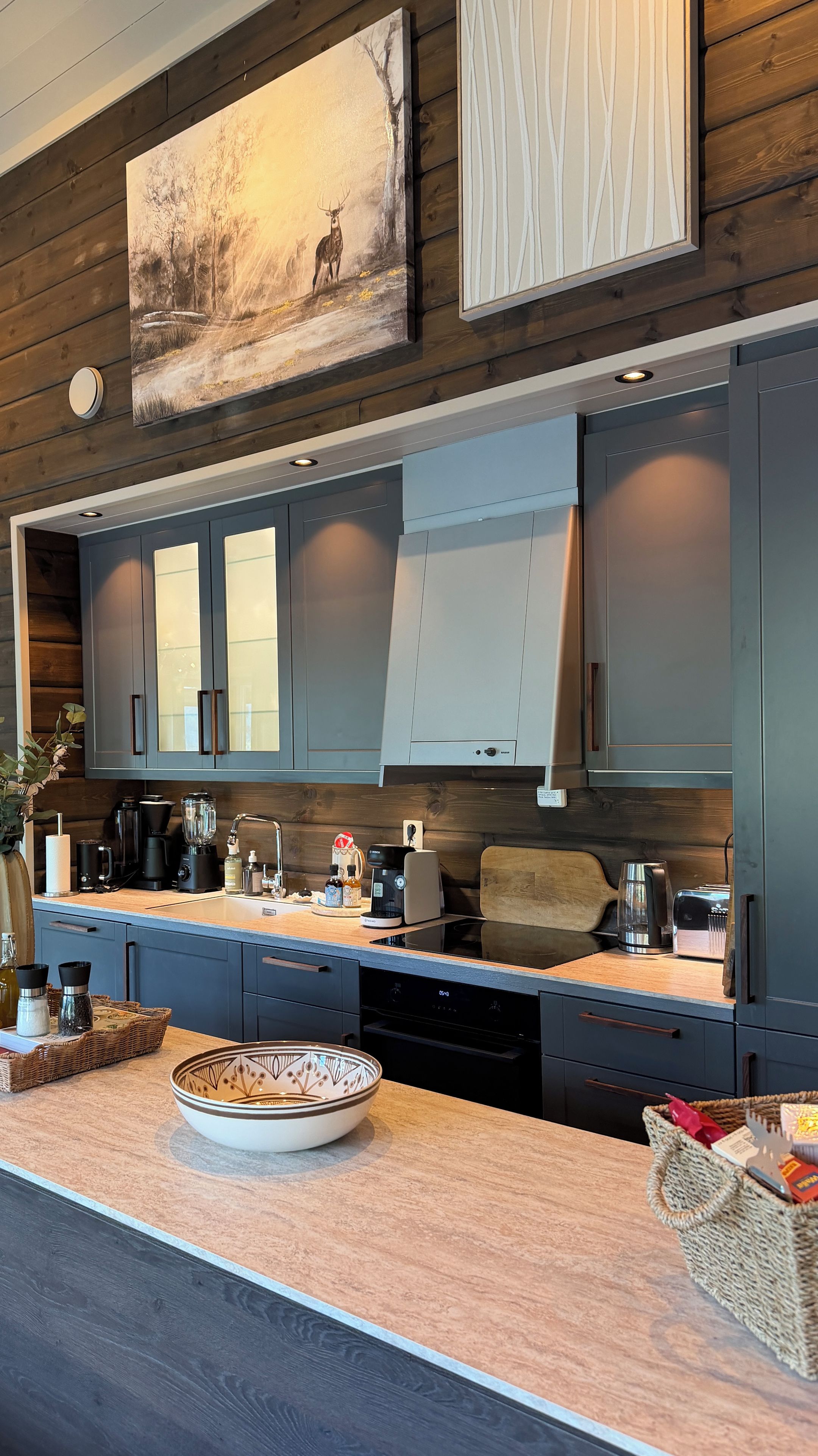 A modern kitchen with dark cabinetry, a central island, and a painting above.