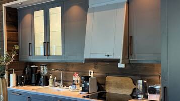 A modern kitchen with dark cabinetry, a central island, and a painting above.